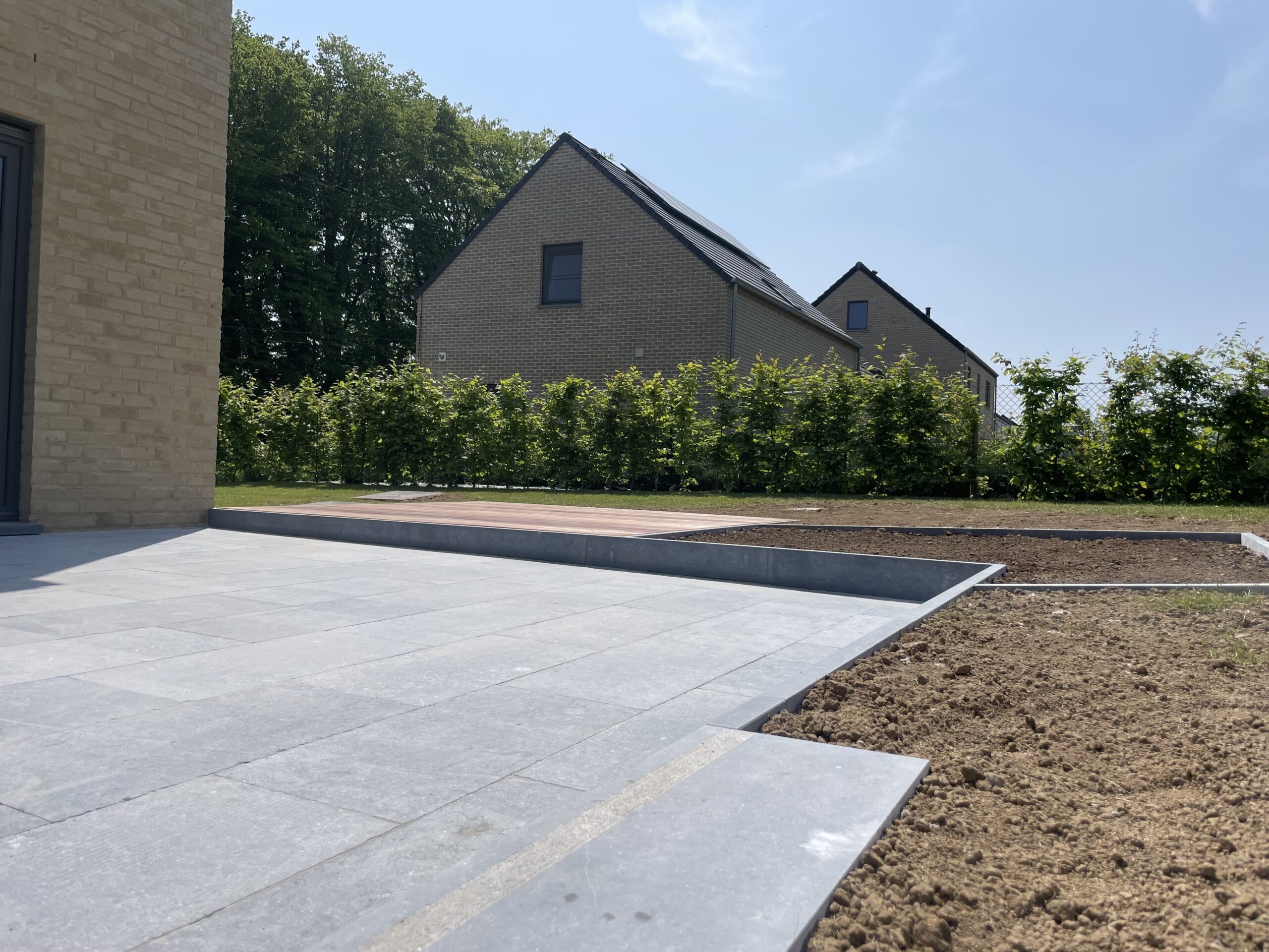 Terrasse en pierre bleue belge, bois exotique, can niveaux discret et plantations. Portail et parking sur l'avant