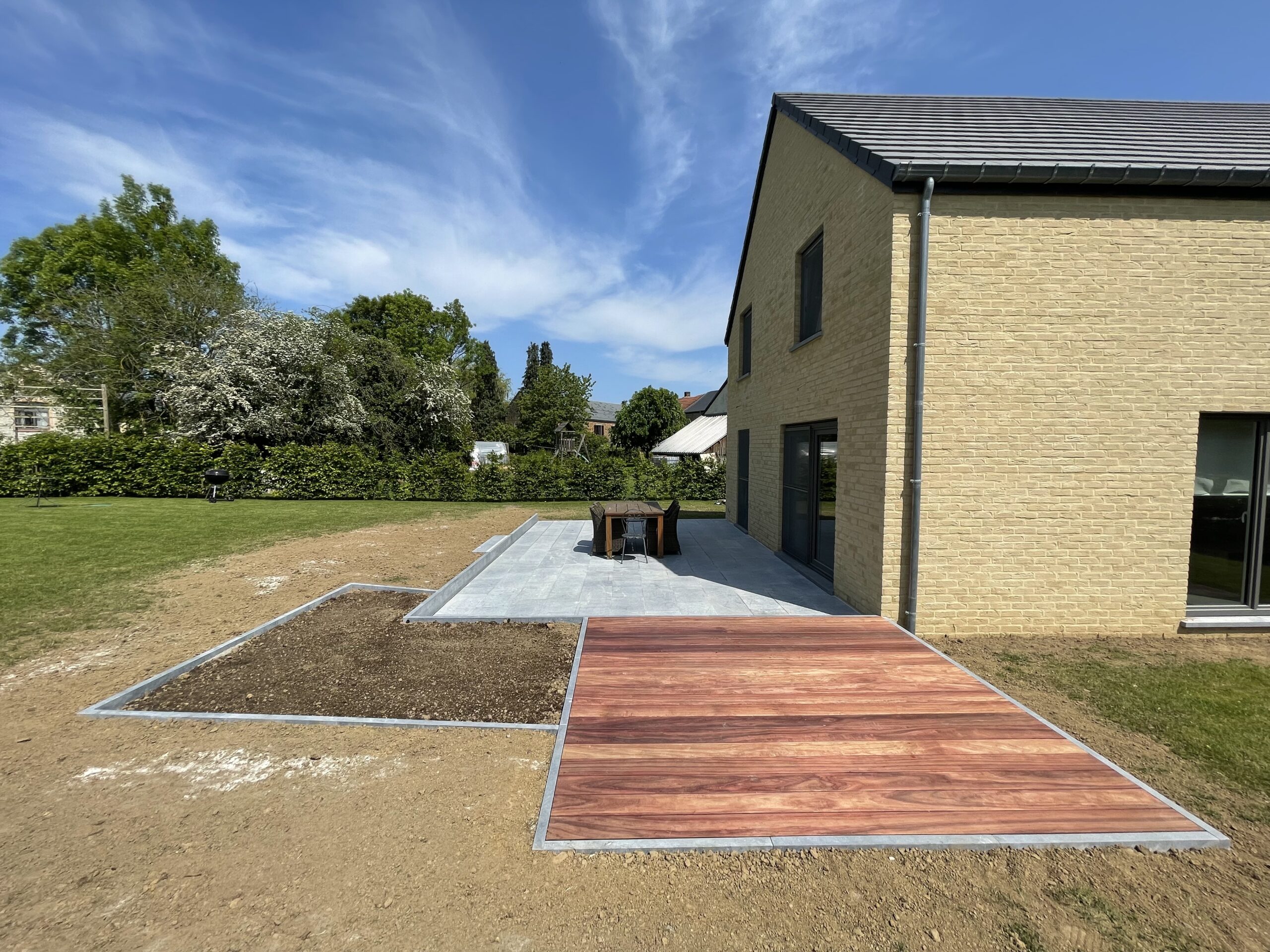 Terrasse en pierre bleue belge, bois exotique, can niveaux discret et plantations. Portail et parking sur l'avant