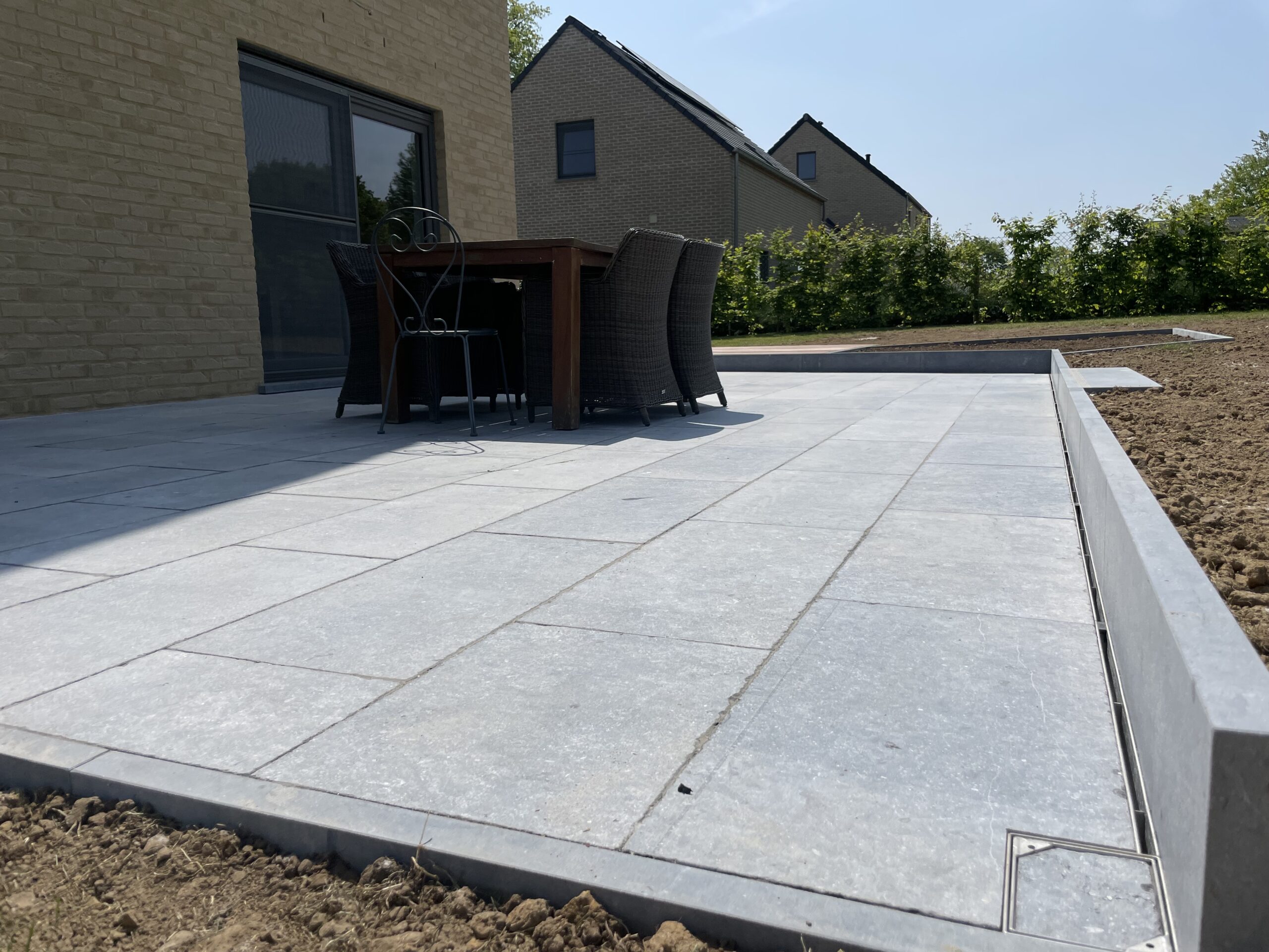 Terrasse en pierre bleue belge, bois exotique, can niveaux discret et plantations. Portail et parking sur l'avant